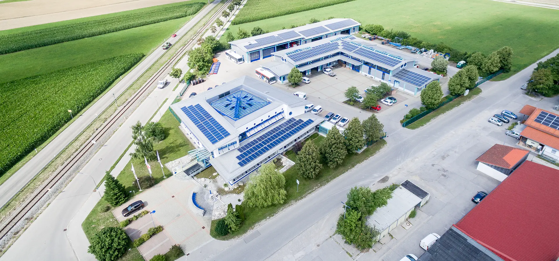 Luftaufnahme des Werkgeländes der Stadtwerke Bad Wörishofen. Das Hauptgebäude und die Hallen sind umgeben von grünen Bäumen und Wiesen.