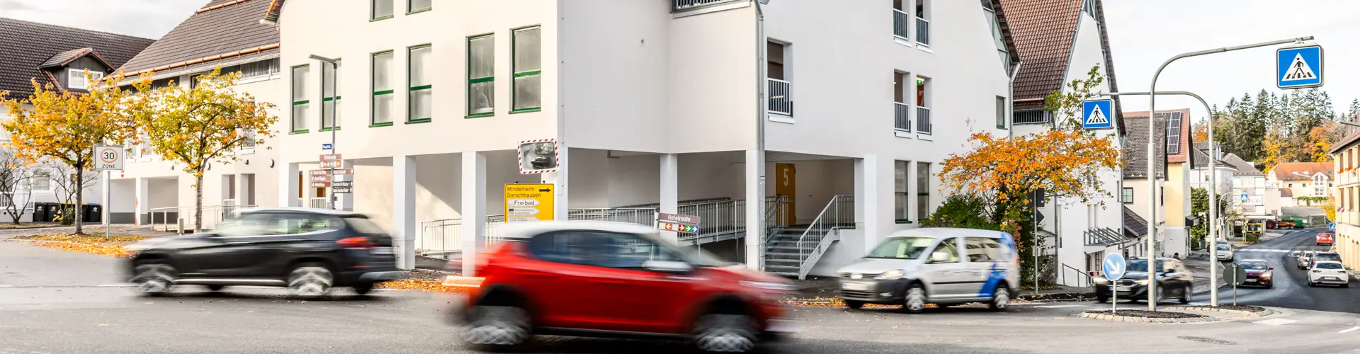 Ein Parkhaus in Bad Wörishofen im Herbst. Davor fahren mehrere Autos auf der Straße vorbei.