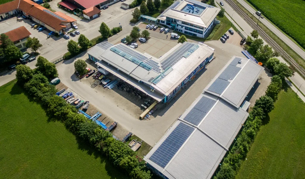 Luftaufnahme des Werksgeländes mit Blick auf die Dächer der Hallen. Auf den Dächern sind Photovoltaikanlagen montiert.