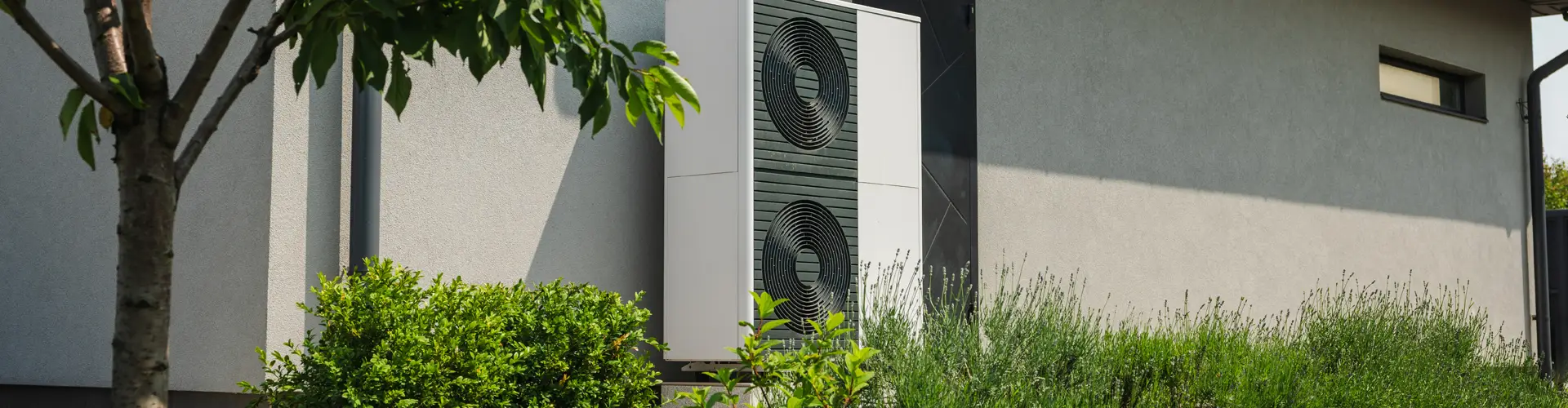 Wärmepumpe vor einem Haus mit Garten